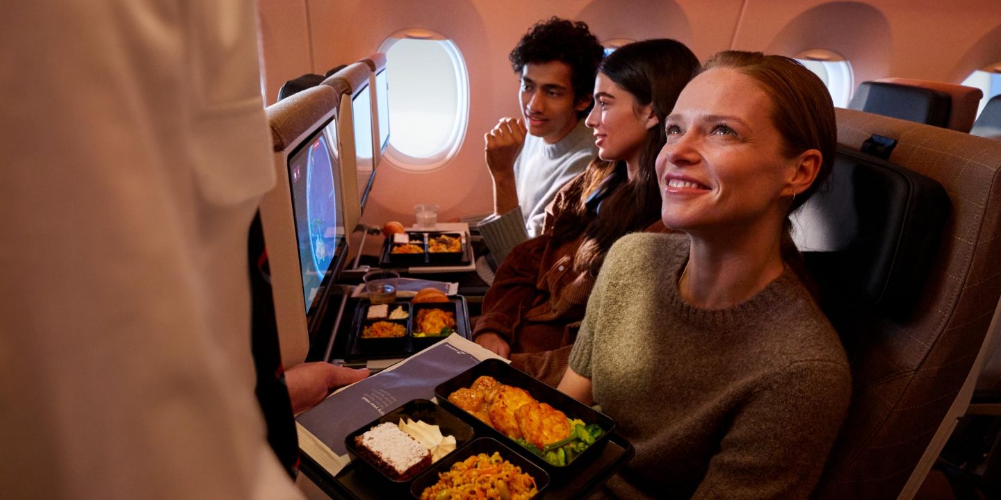 Flight attendant serves fresh, appealing meals to happy passengers onboard.