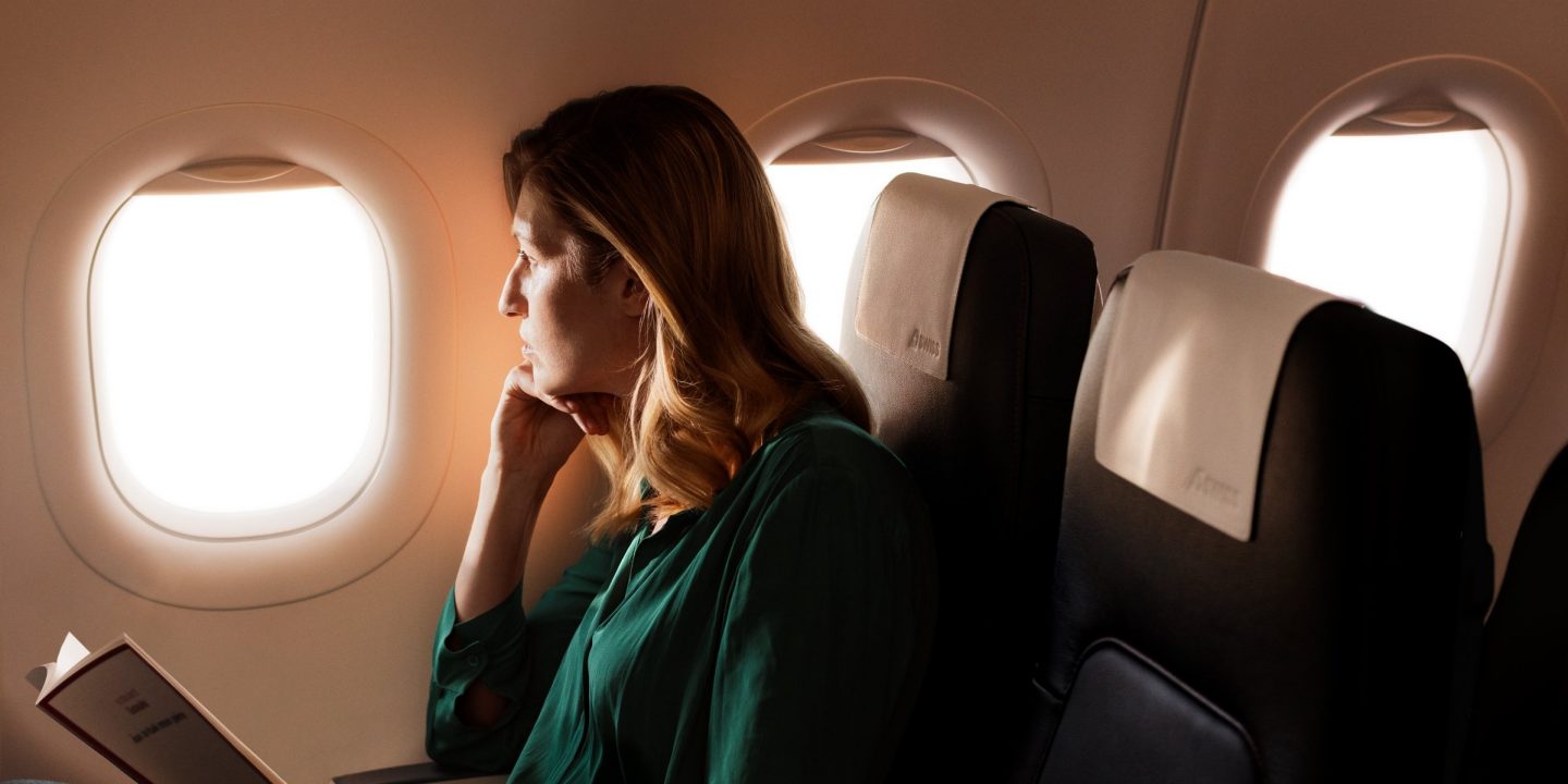 A woman looking outside the window in an airplane seat.