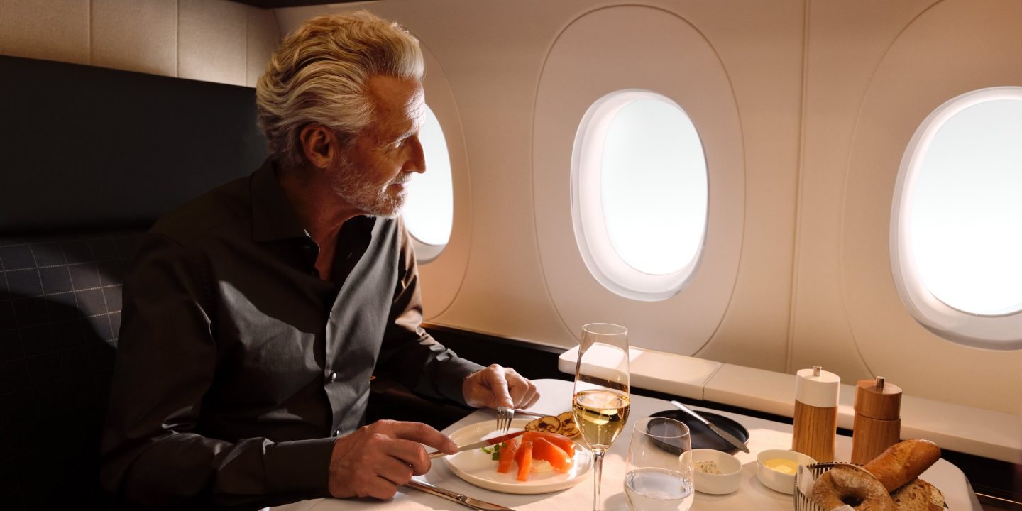 Man enjoys premium inflight dining and champagne by the window.
