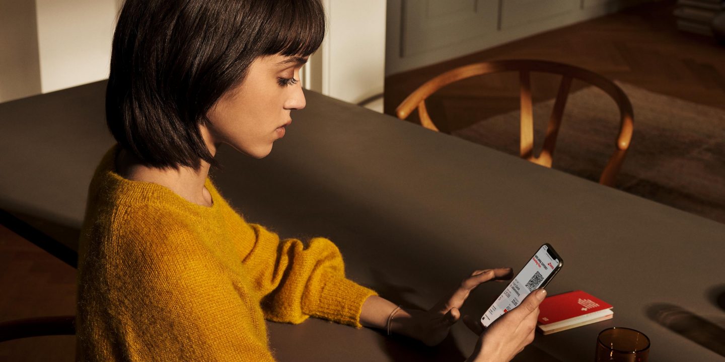 A woman sitting at a table at home using her mobile phone.