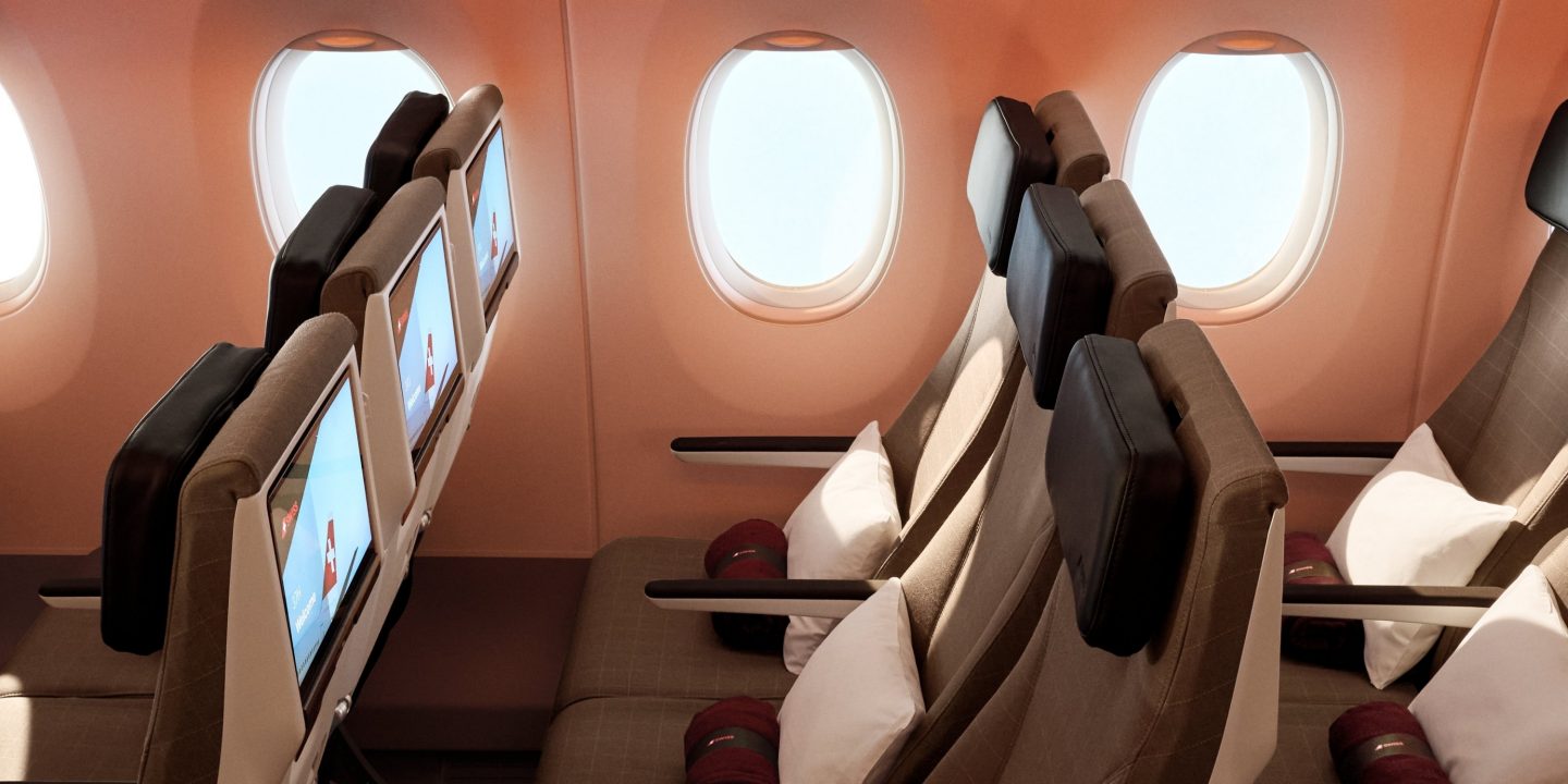 Blick auf die moderne Flugzeugkabine mit bequemen Sitzen und Bildschirmen.