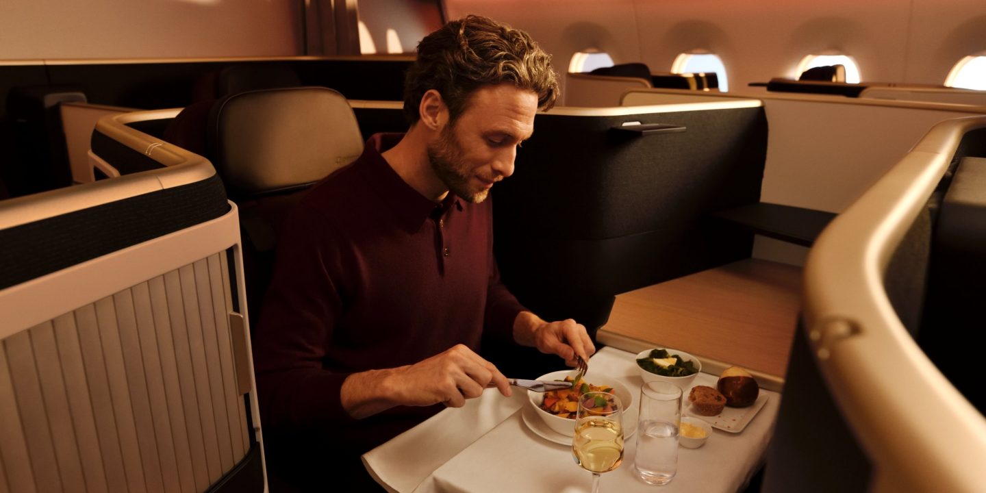 Man enjoys a delicious meal and wine in the comfort of a premium flight cabin.