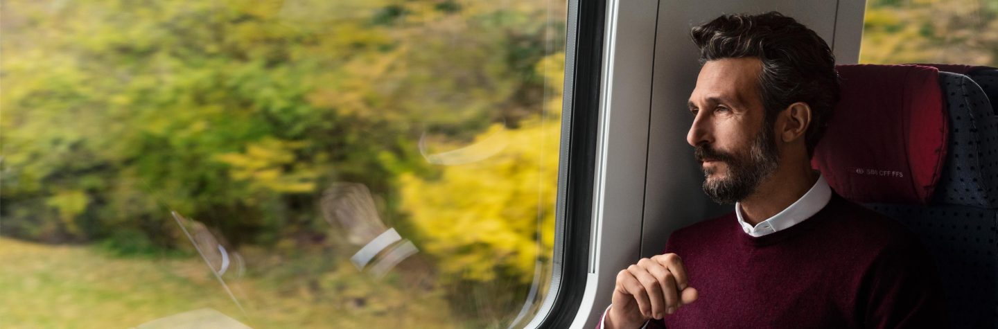 A man sitting at the window of a moving train.