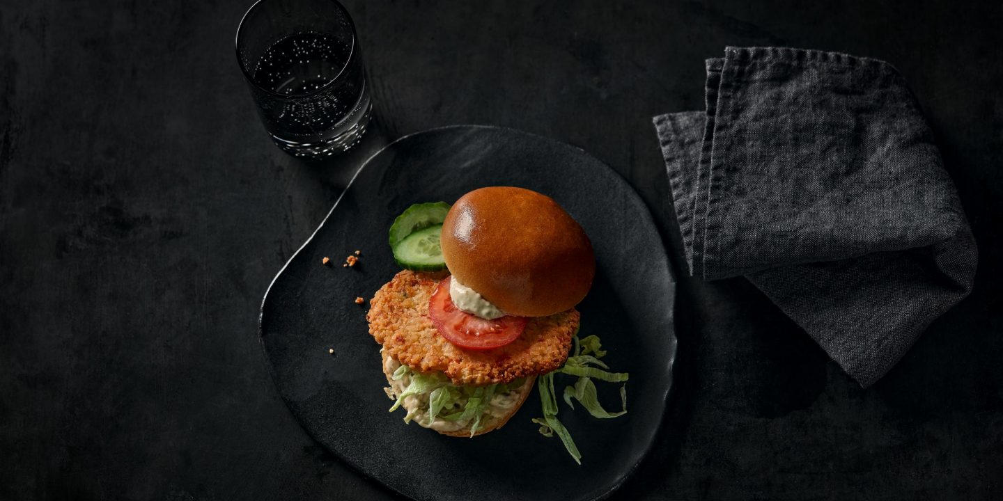 A burger on a black plate.