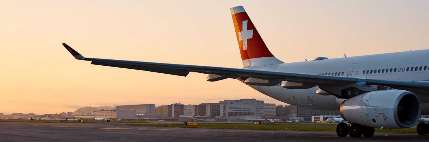 Rear view of a SWISS Airbus A330 on the airport tarmac during sunset.