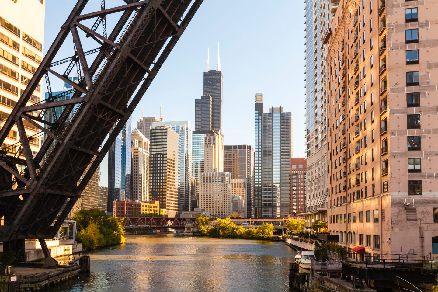 View of Chicago and its river, with skyscrapers and a metal bridge.