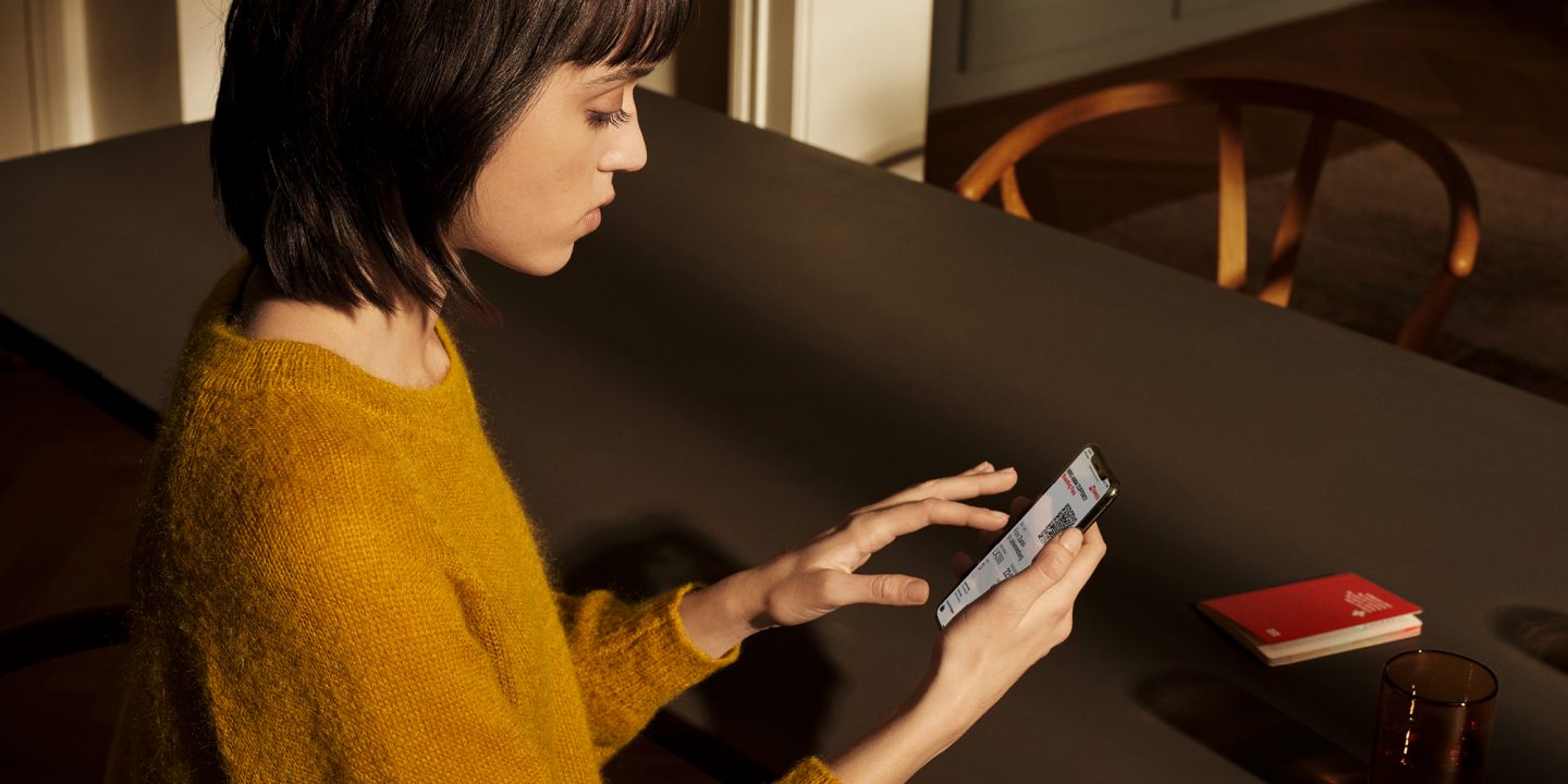 A woman at a table with a phone and a book, seeking quick help with her ticket refund.