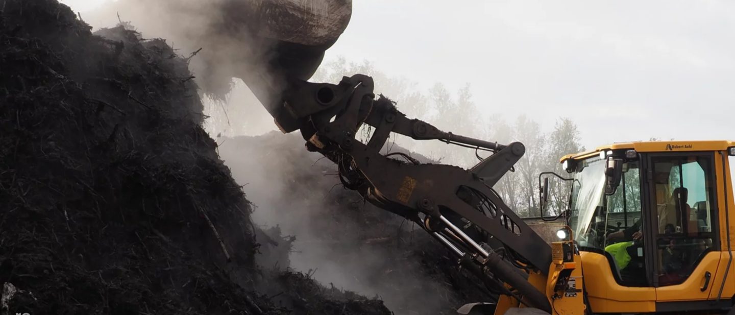A large machine dumps a pile of earth.