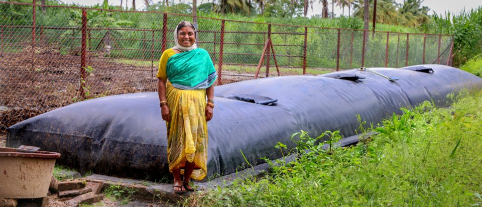 A woman is standing next to a large black tank.