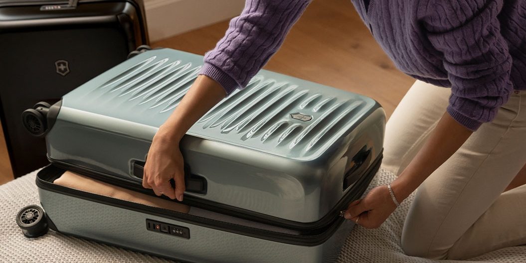  A woman sets a suitcase on a bed, ready to send her luggage ahead with AirPortr.