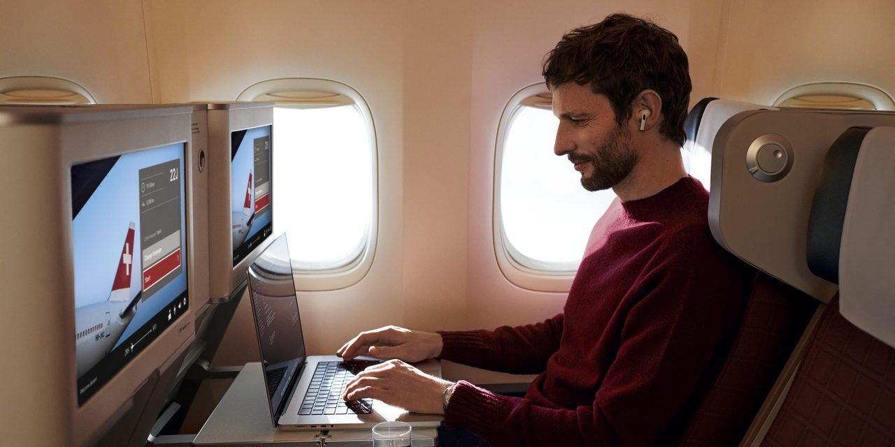 A man working on a laptop on a plane.