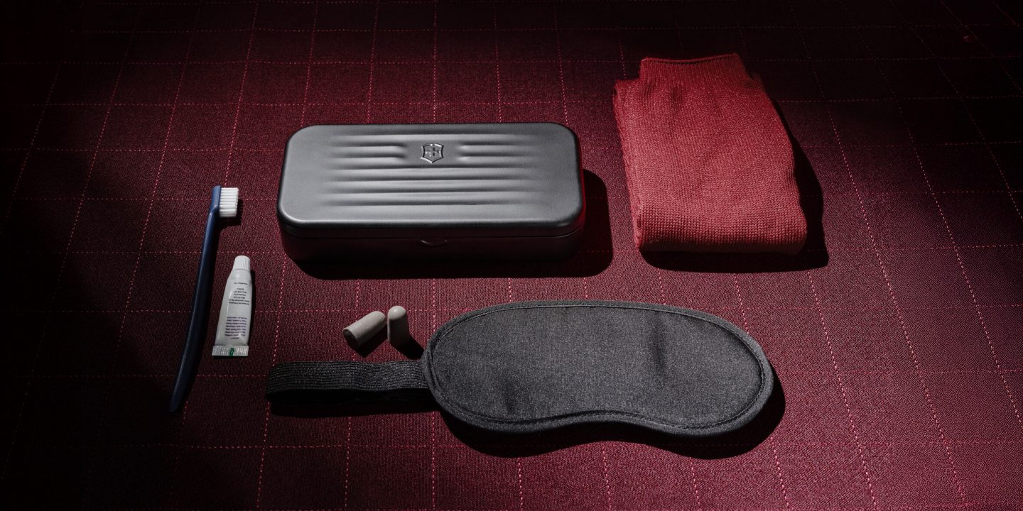 Airline amenity kit with Victorinox case, eye mask, earplugs, toothbrush, toothpaste, and socks.