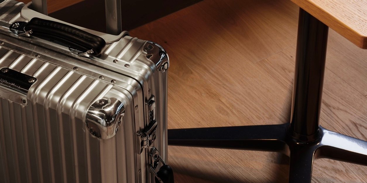A silver suitcase resting on a wooden floor, showcasing its sleek design and sturdy build.