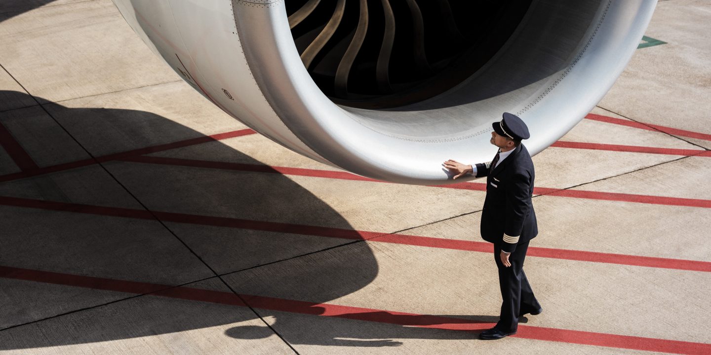 A man in uniform stands beside an airplane engine, highlighting travel regulations for your journey.