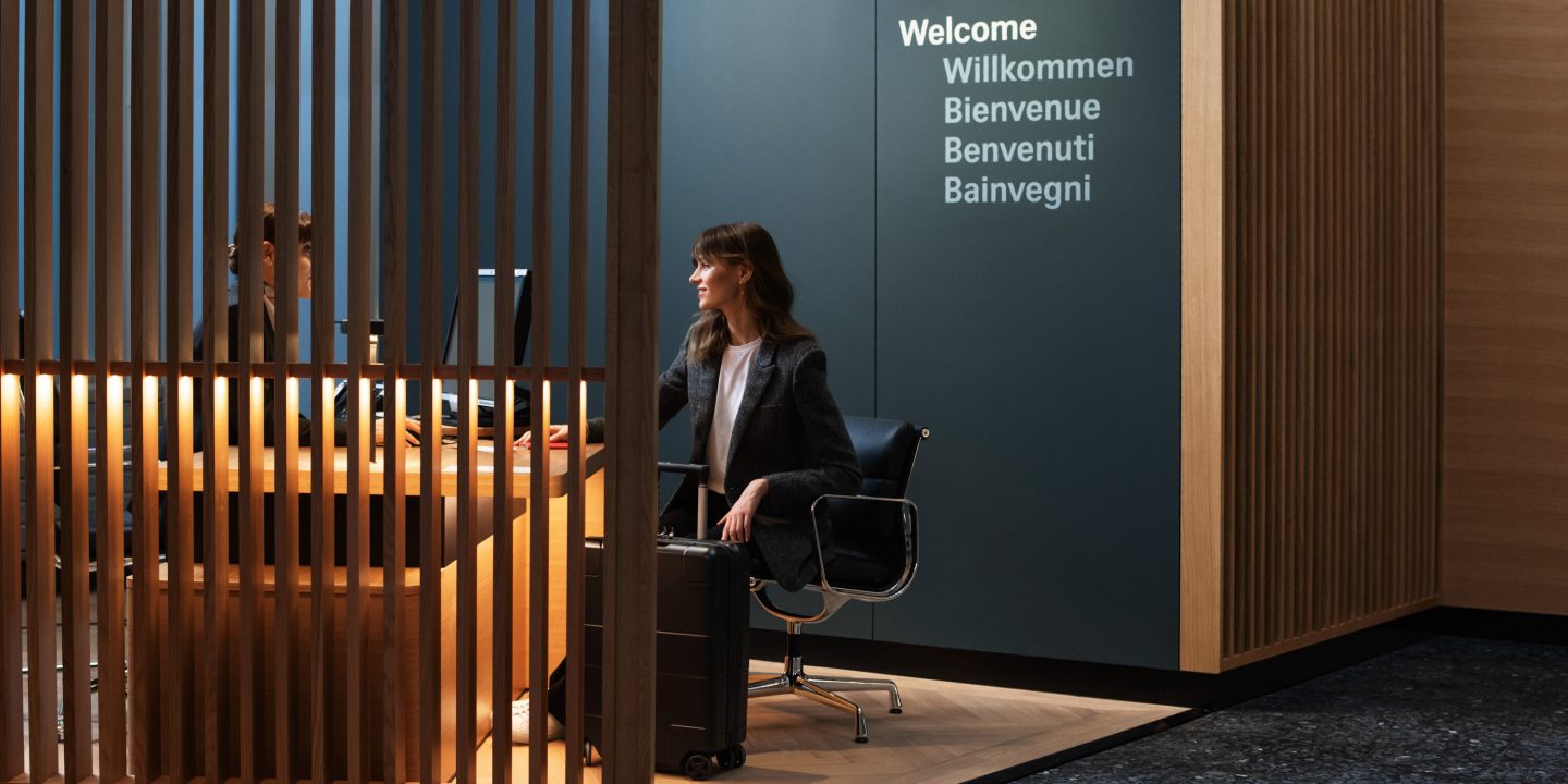 A woman at a desk in a room with a wooden partition, concentrating on her work.