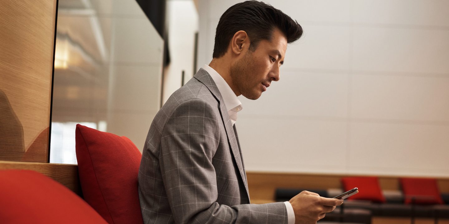 Well-dressed man checks phone in comfortable lounge.