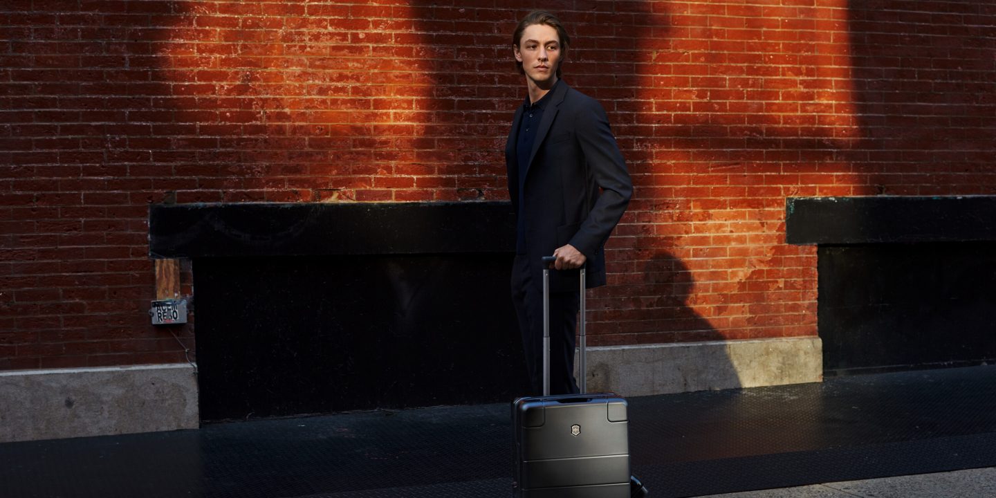 Man in suit with black carry-on suitcase, ready for travel.