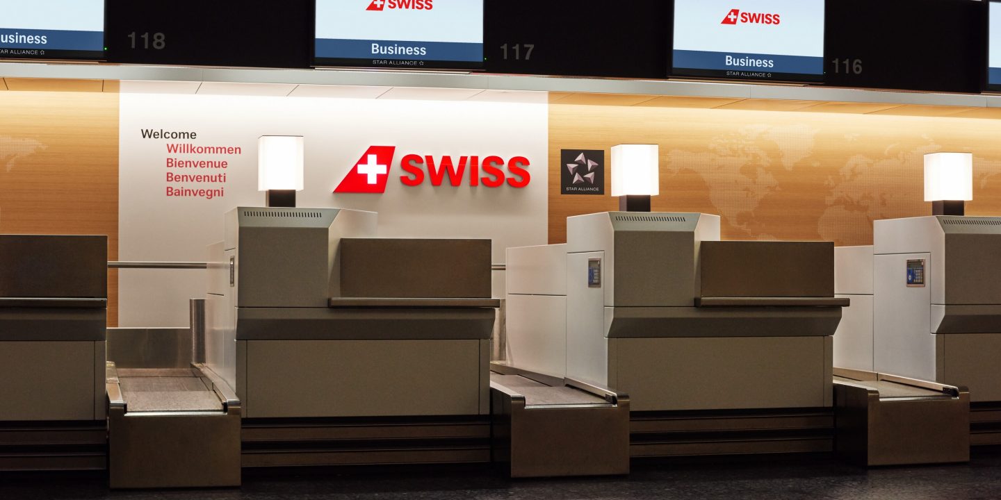 A row of luggage carts lined up, ready for travelers at an airport check-in area.