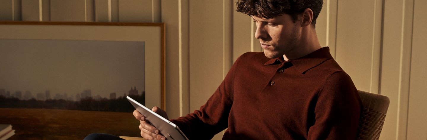 A man using a tablet in a relaxed indoor setting.
