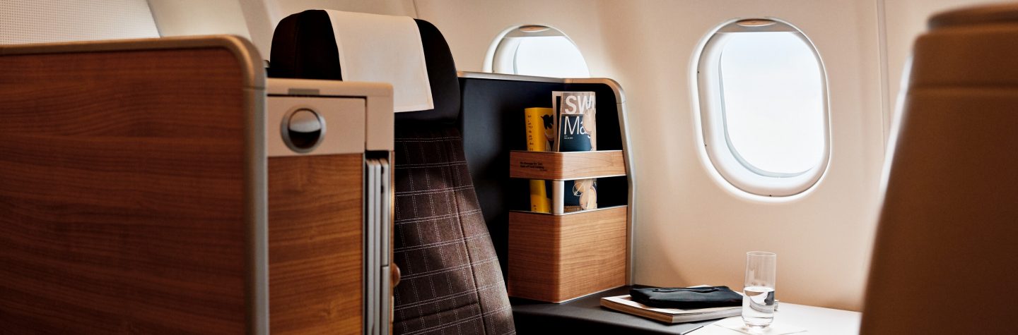 Elegant airline cabin interior with wood accents, window, and personal amenities.