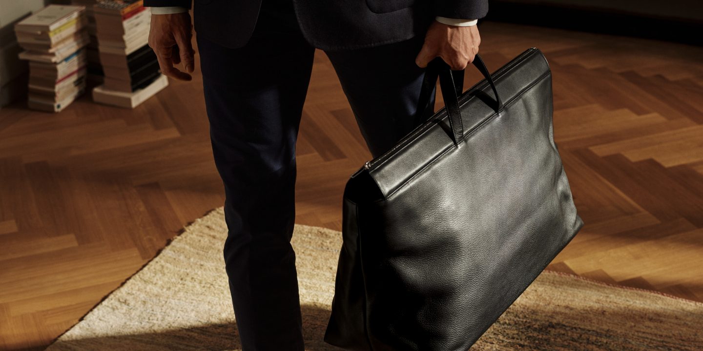 A man in a suit holding a black briefcase, ready for travel or a business meeting.