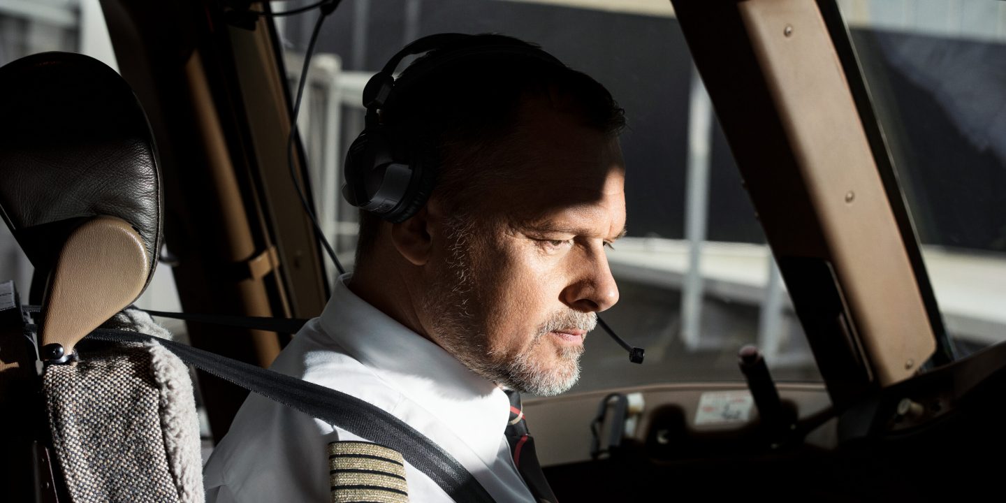 Pilot in cockpit focused on controls.
