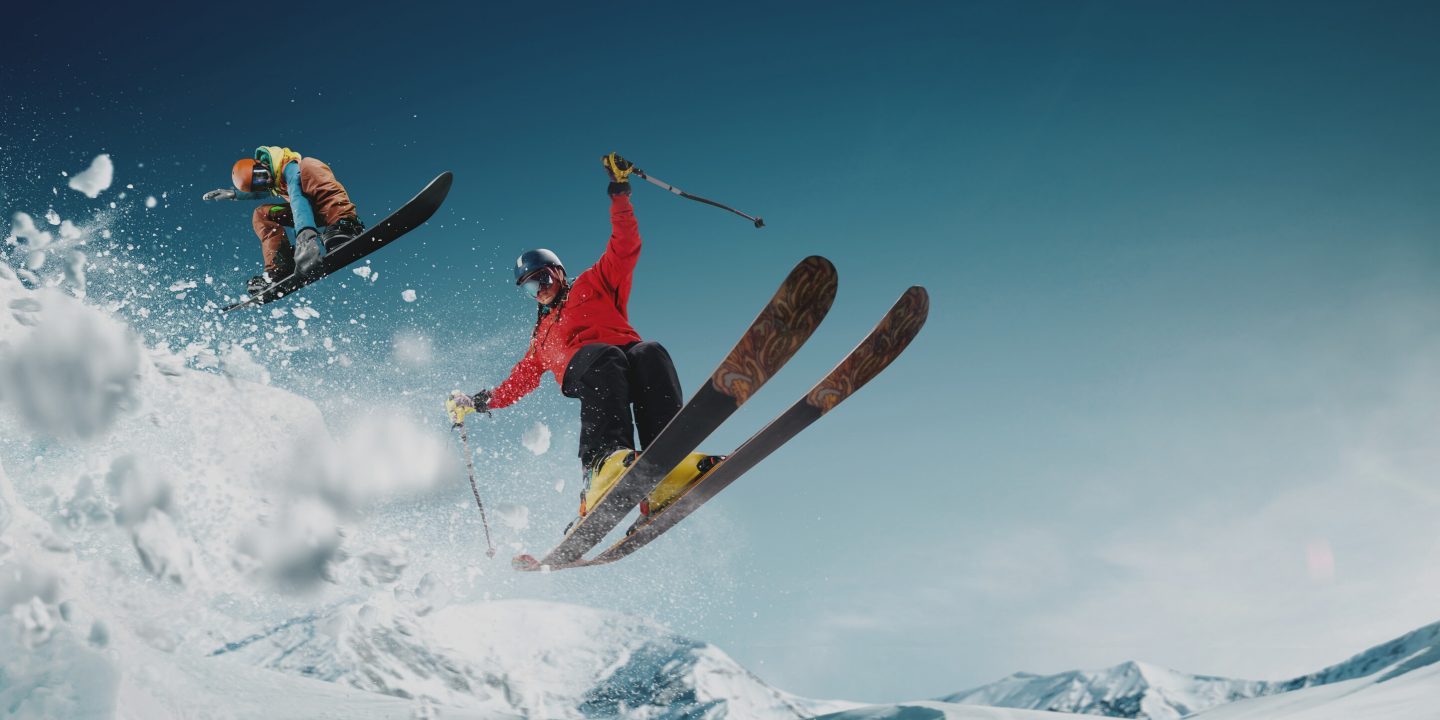 Two skiers launch off a snowy slope, capturing winter thrills.