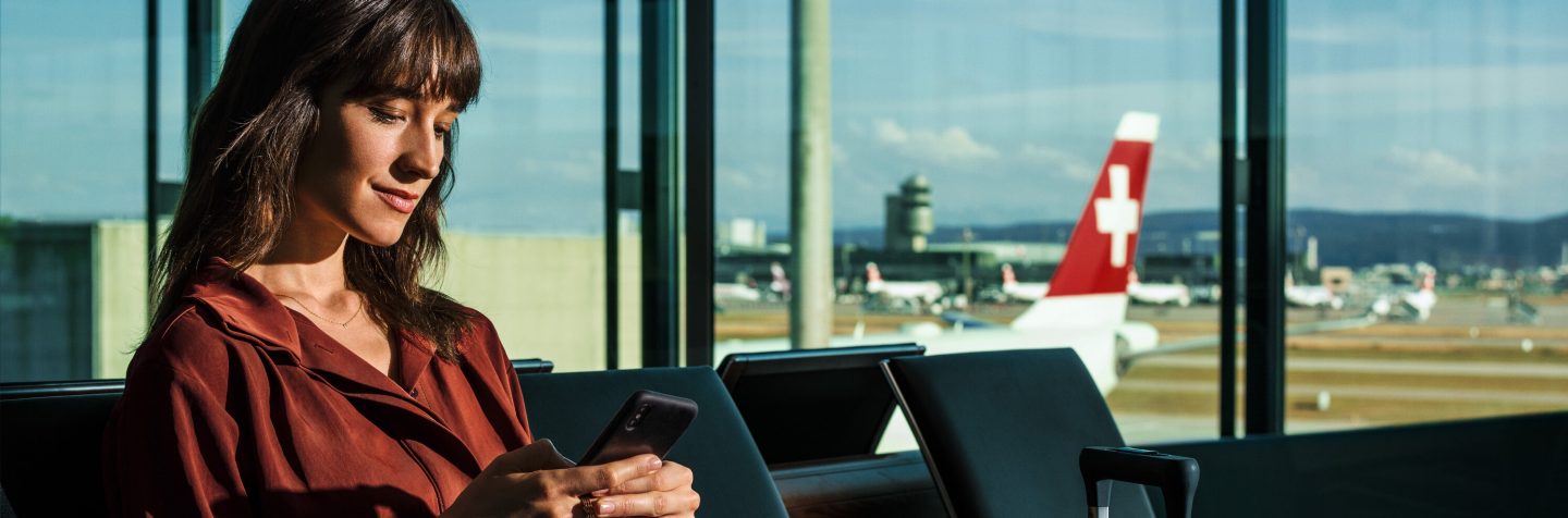A woman at the airport checking her phone amid delayed and cancelled flights.