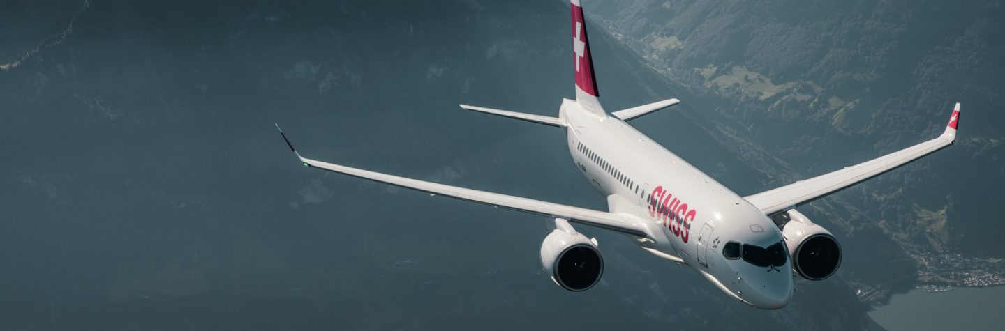 A SWISS aircraft flying over a mountainous landscape.
