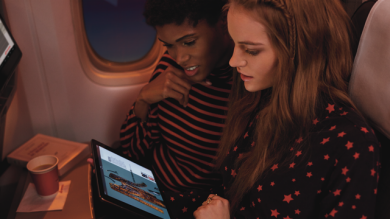 Two women looking at an ipad in the plane.